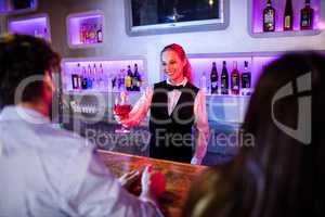 Barmaid serving drink to man