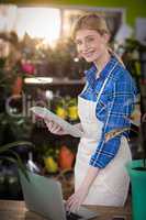 Female florist using laptop while holding clipboard