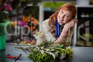 Happy female florist leaning in flower shop