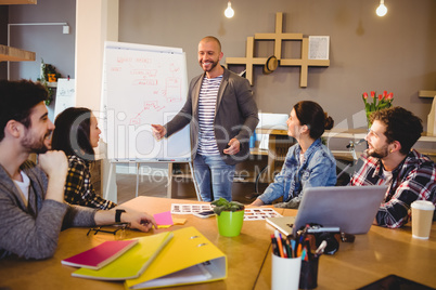 Male graphic designer discussing chart on white board with cowor