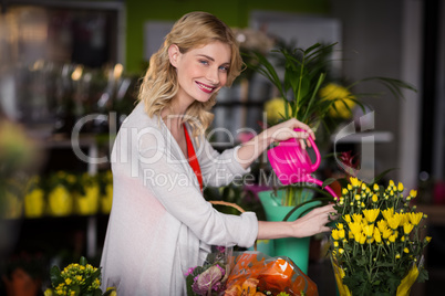 Happy female florist watering flowers