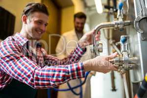 Maintenance workers examining brewery machine