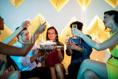 Group of smiling friends toasting a glass of champagne while cel
