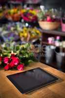 Bunch of red roses and digital tablet on the wooden table