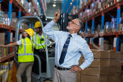 Serious manager pointing shelves with hand on hips