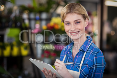 Portrait of female florist writing on clipboard