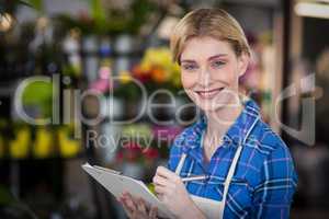 Portrait of female florist writing on clipboard