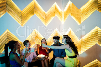 Group of smiling friends toasting a glass of champagne while cel