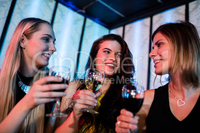 Smiling friends enjoying while having wine