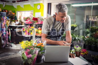 Male florist using mobile phone