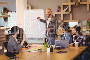 Male graphic designer discussing chart on white board with cowor