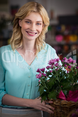 Happy female florist holding basket of flowers