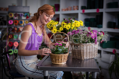 Female florist preparing basket of flowers