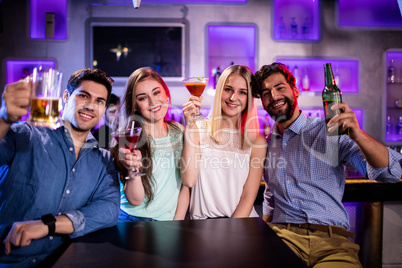 Group of friends showing cocktail, beer bottle and beer glass at
