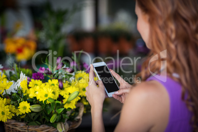 Female florist taking photogrpah of flower basket