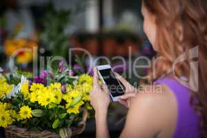 Female florist taking photogrpah of flower basket