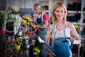 Happy female florist watering flowers