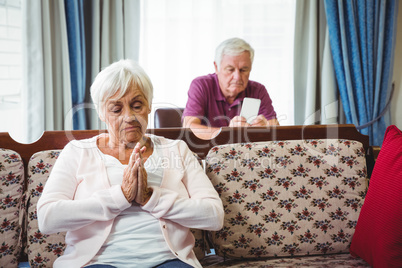 Serious seniors sitting on couch and chair