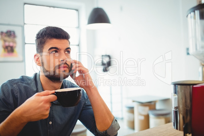 Graphic designer having coffee while talking on mobile phone