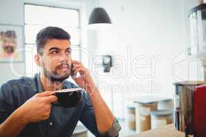 Graphic designer having coffee while talking on mobile phone