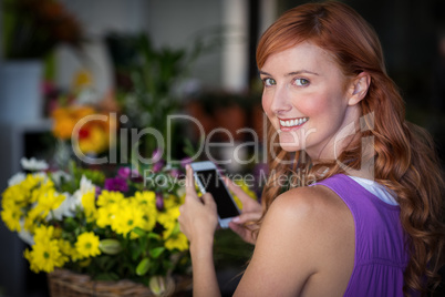 Female florist taking photogrpah of flower basket