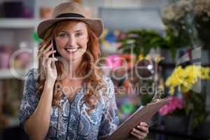 Smiling female florist taking order on mobile phone