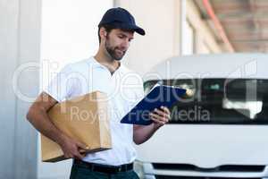 Portrait of delivery man is holding a cardboard box and looking