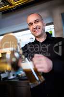 Brewer filling beer in beer glass from beer pump