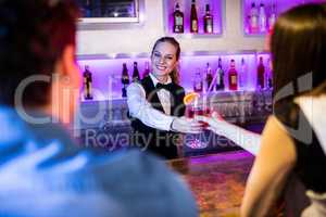 Barmaid serving drink to woman