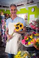 Male florist holding bunch of yellow sunflower