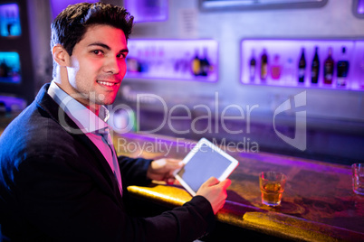 Man using digital tablet while having whisky at bar counter