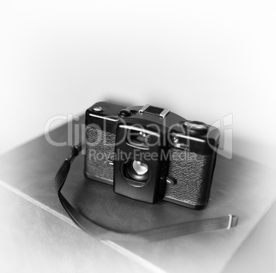 Black and white vintage camera with strap vignette bokeh backgro