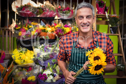 Male florist holding bunch of flowers at flower shop