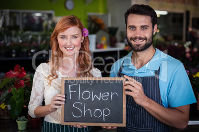 Portrait of couple holding slate with flower shop sign