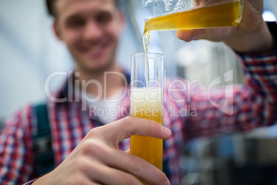 Brewer pouring beer in hydrometer cylinder