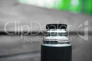Horizontal black and white thermos with green bokeh background