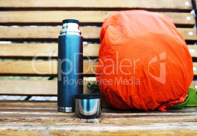 Horizontal thermos with backpack on bench bokeh background