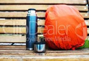 Horizontal thermos with backpack on bench bokeh background
