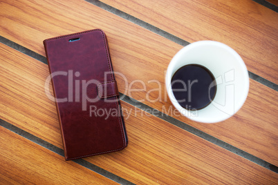 Wooden table in cafe with cell phone and coffee background