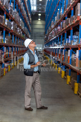 View of worker is looking shelves and holding a clipboard