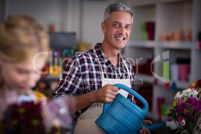 Happy male florist watering flowers