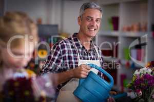 Happy male florist watering flowers