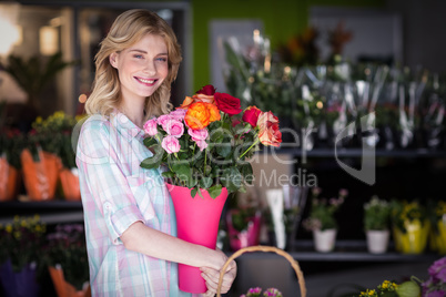 Happy female florist holding flower vase