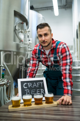 Portrait of brewer with four glasses of craft beer on table