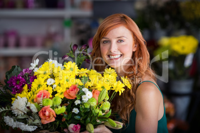 Happy female florist holding bunch of flowers