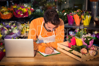 Male florist noting order in notepad