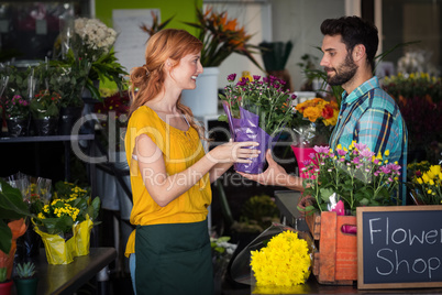 Female florist giving flower bouquet to man