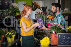 Female florist giving flower bouquet to man