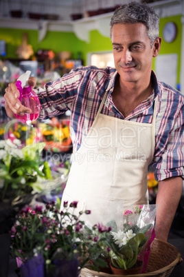 Male florist spraying water on flowers