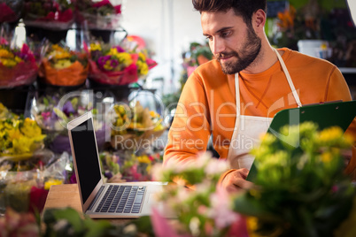 Male florist checking order in laptop